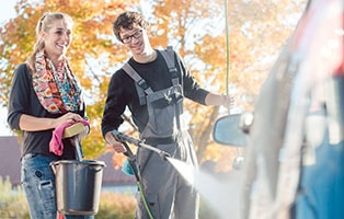 Young couple wash a car with pressure washer.