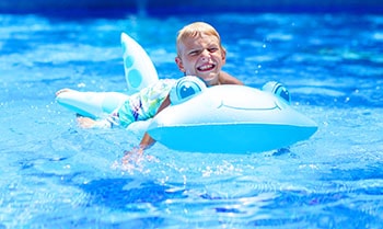 Boy swims in the pool on inflatable turtle.